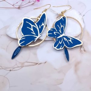 Affirmez votre style avec l'éclat des boucles d'oreilles "Papillon Saphir". Un duo graphique et coloré, alliant la noblesse du bleu cobalt à une structure dorée contemporaine.