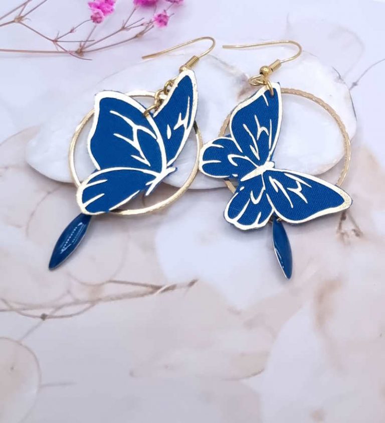 Affirmez votre style avec l'éclat des boucles d'oreilles "Papillon Saphir". Un duo graphique et coloré, alliant la noblesse du bleu cobalt à une structure dorée contemporaine.