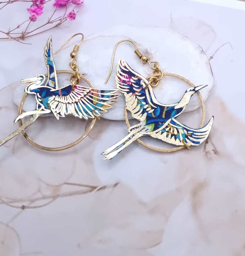 Affirmez votre personnalité avec les boucles d'oreilles "Envolée Bleue". Une création originale en acier inoxydable et tissu, alliant éclat doré et motifs colorés pour un look bohème irrésistible.
